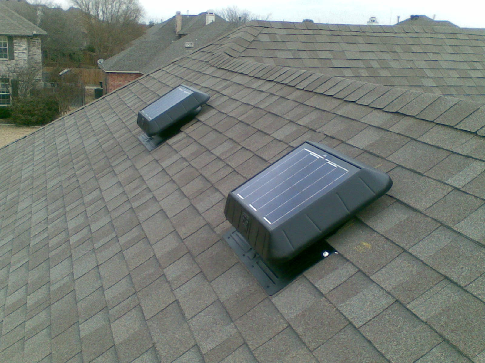 Solar attic fans on a roof cooling an attic and a home